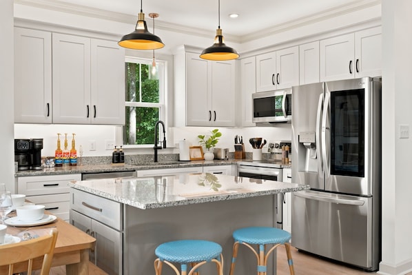 A modern kitchen with stainless steel appliances, white cabinetry, and a granite countertop.