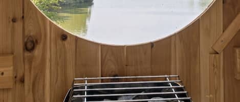 A sauna with a circular window offering a view of a river and forest.
