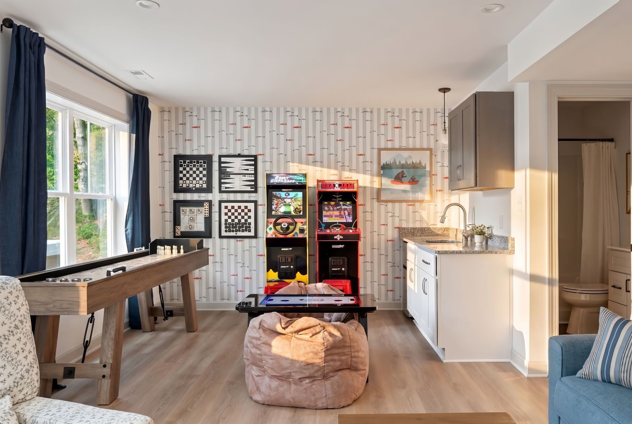 Een gezellige woonkamer met een pooltafel, een loungestoel en een keukenhoek met een spoelbak en kastjes.