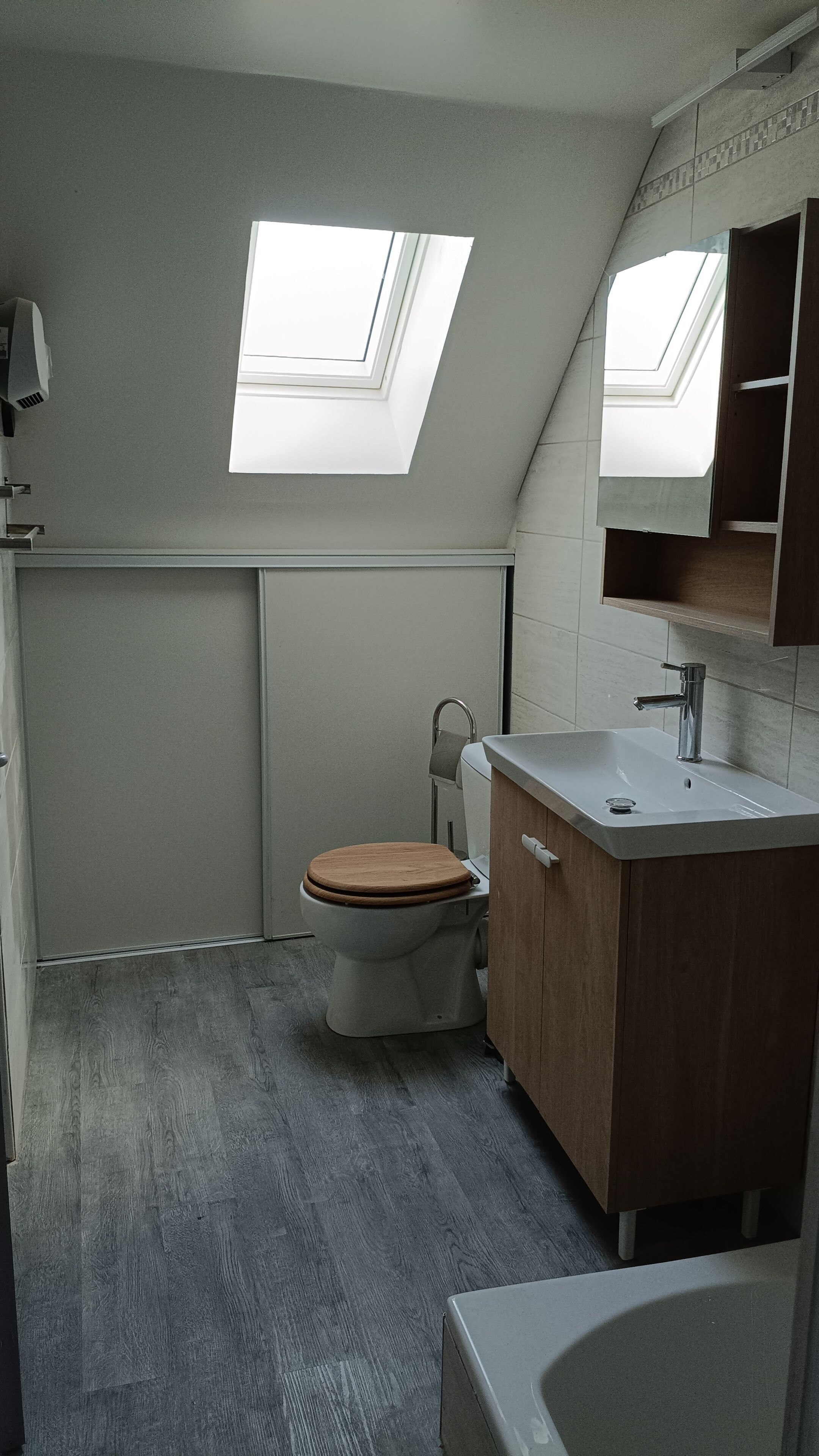 Een badkamer met dakraam, toilet, wastafel en bad.