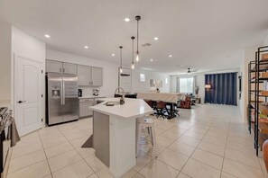 A modern kitchen with a central island, stainless steel appliances, and recessed lighting. - Contemporary Hideaway • PS4 Console & Games • Fire Pit & Turf (North Las Vegas)