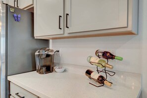 Eine Küche mit Kaffeemaschine, Weinflaschen an einem Ablagefach und einer Schüssel auf der Arbeitsplatte.