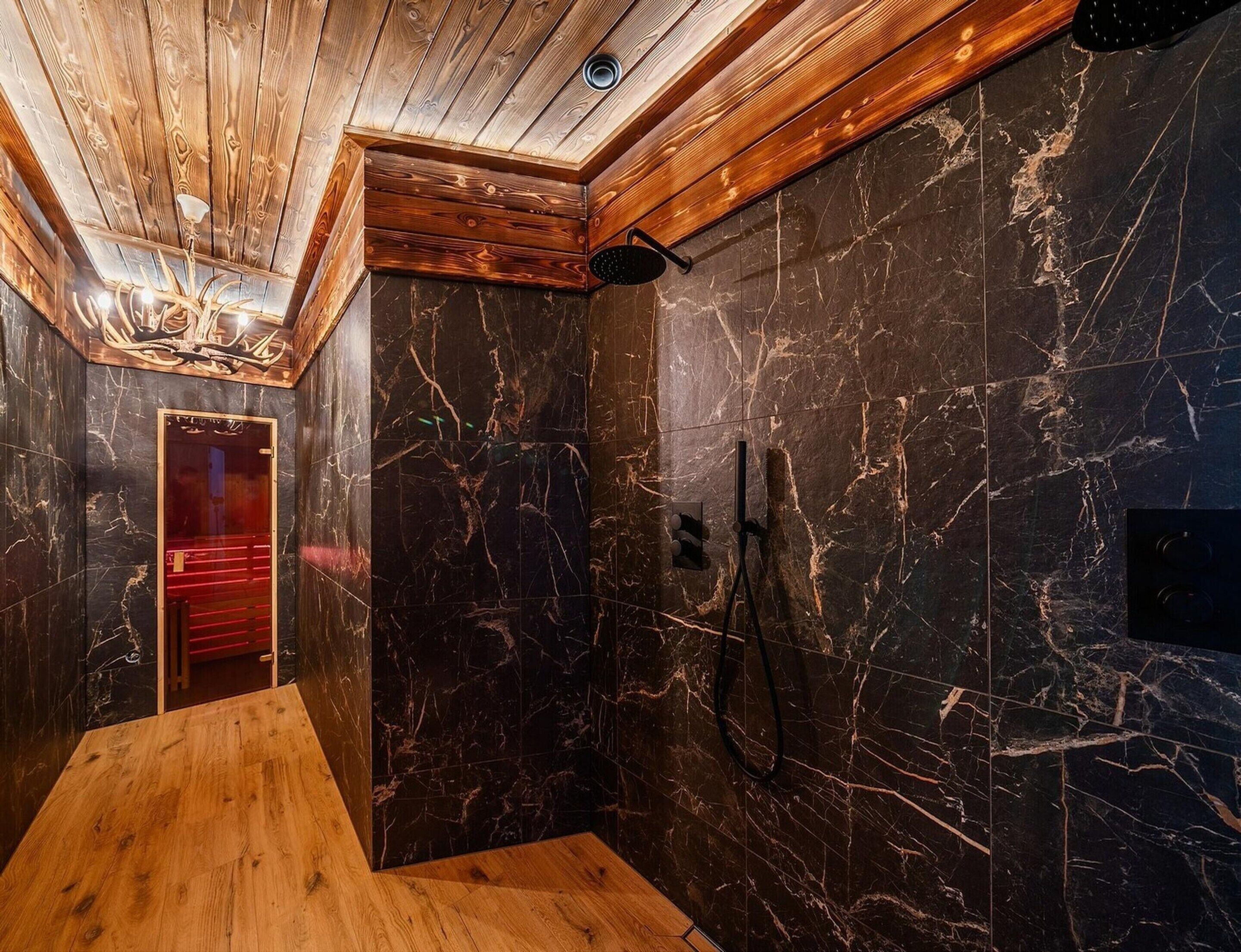A modern bathroom with a wooden ceiling, marble walls, and a shower area.