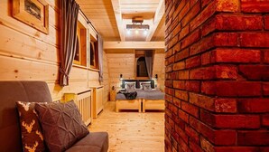 A cozy wooden cabin interior with a sofa, a dining table, and a brick wall. - A Large Mountain-style House With a spa Area (Poronin)
