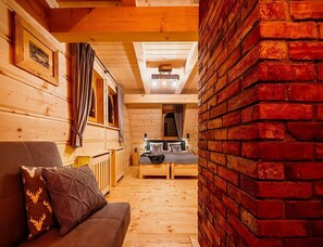 Ein gemütliches Holzhaus-Interieur mit einer Couch, einem Esstisch und einer Ziegelwand.