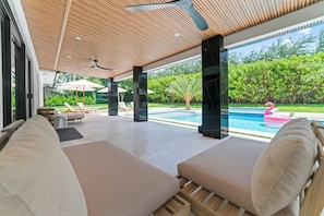 Ein moderner Außenbereich mit Lounge-Möbeln, einem Pool, einer Holzbalkendecke und bequemen Sitzgelegenheiten.