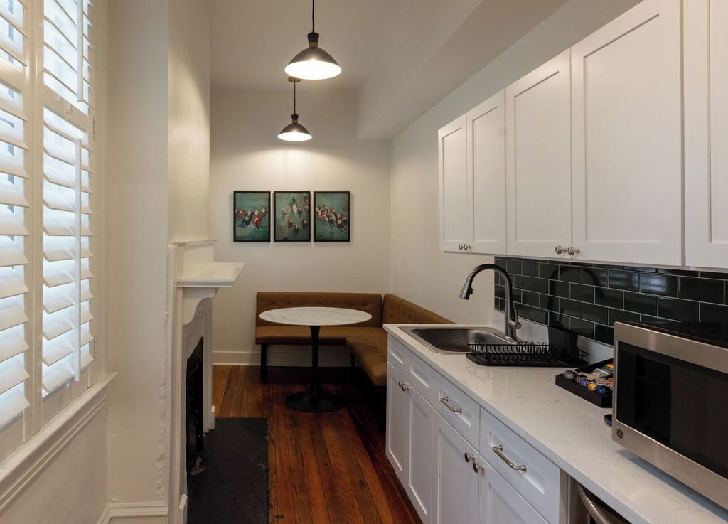 A compact kitchen with white cabinets, a black countertop, and a stainless steel microwave.