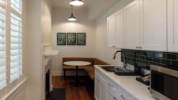 A compact kitchen with white cabinets, a black countertop, and a stainless steel microwave.