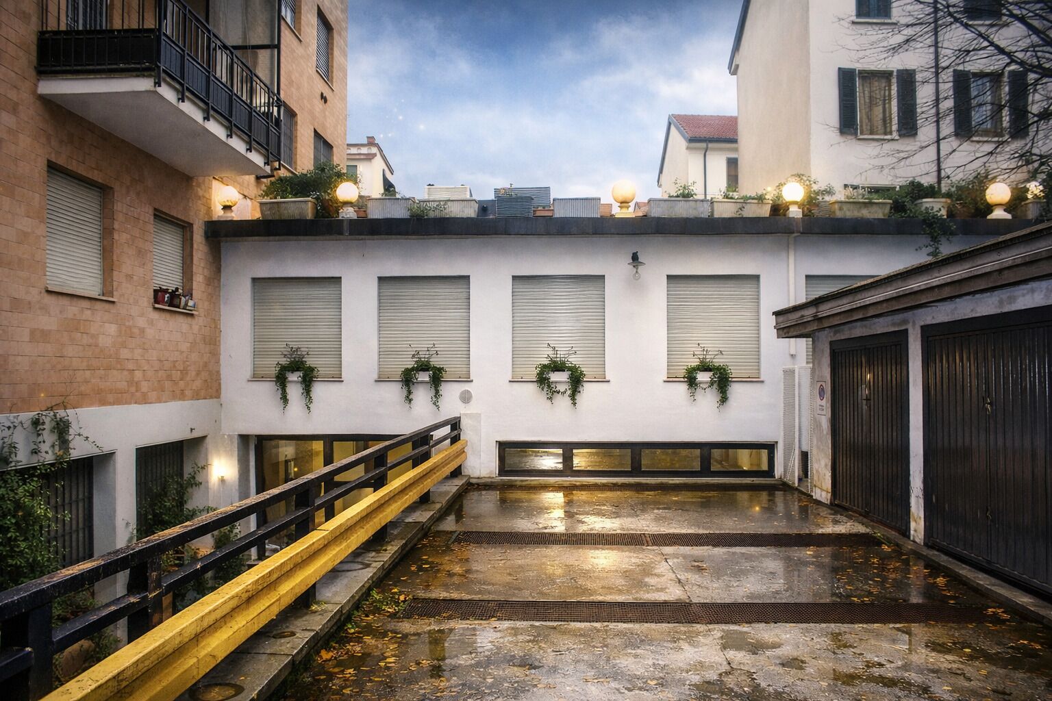 A narrow alleyway with a yellow railing, a wet ground, and buildings with shutters and hanging plants.