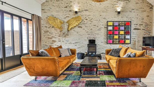 A spacious living room with two sofas, a coffee table, and a colorful rug. - Floreal : Villa 1900 au Coeur de St Gilles (Saint-Gilles-Croix-de-Vie)