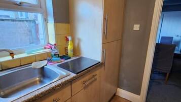 A kitchen with a window, a sink, cabinets, and a door leading to another room.