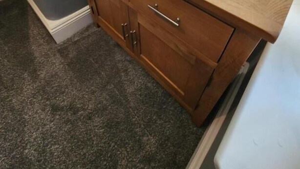 A wooden dresser with drawers and a lamp, situated in a room with a window and a curtain. - The Ivy (Grays)
