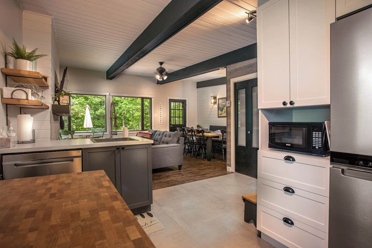 A modern kitchen with a wooden countertop, built-in appliances, and a dining area with a view of greenery.