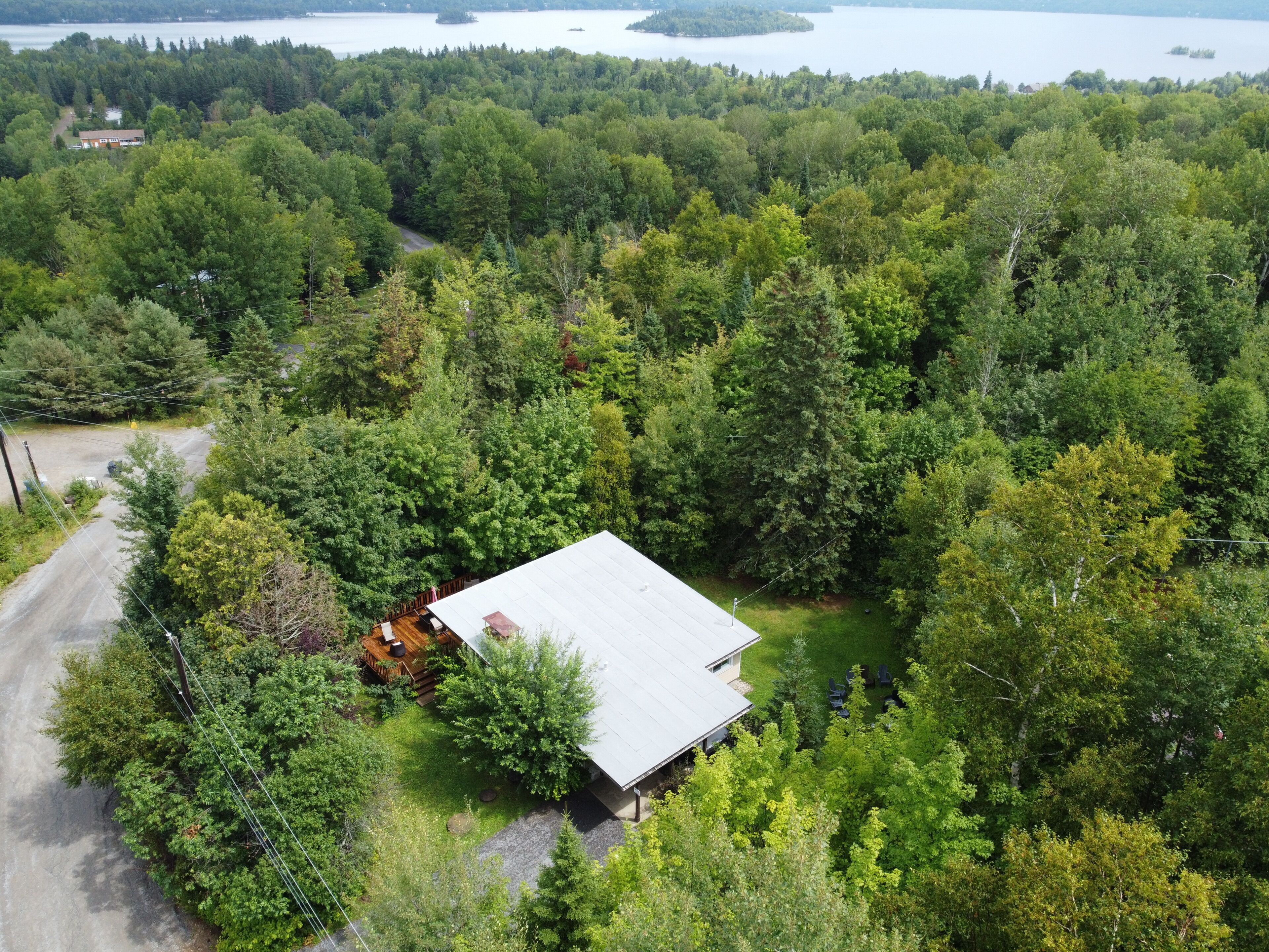 A house surrounded by dense forest with a clear view of a lake in the background.