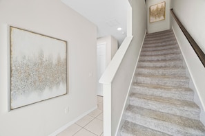 A staircase with a handrail and a wall with a framed picture. - Private Pool •Free Parking •Cozy Solara Resort Home Near Disney •Sleeps 12 Guest (Kissimmee)