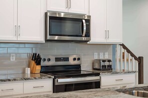 Een moderne keuken met roestvrijstalen apparatuur, witte kasten en een granieten aanrecht.