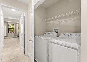 A laundry room with two front-loading washing machines, a metal drying rack, and a door leading to another room. - 12 Mi to Disney! Resort Pool, Gym (Davenport)