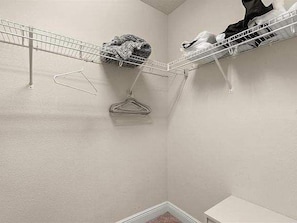 A corner of a room with a metal wire shelf holding hangers and a small white cabinet. - 12 Mi to Disney! Resort Pool, Gym (Davenport)