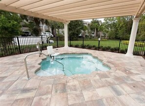 A covered swimming pool with a curved edge, surrounded by stone tiles, and a metal railing. - 12 Mi to Disney! Resort Pool, Gym (Davenport)