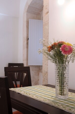 A dining table with a checkered tablecloth, a vase with flowers, and a chair. - L'Oasi Perfetta per Sconnettere: Relax, Comfort e Posizione Strategica (Castellana Grotte)