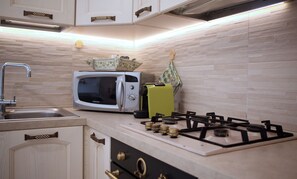 A kitchen with a microwave, toaster, and gas stove. - L'Oasi Perfetta per Sconnettere: Relax, Comfort e Posizione Strategica (Castellana Grotte)