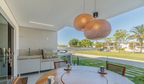 Ein moderner Essbereich im Freien mit einem runden Tisch, Stühlen und einer ungewöhnlichen Hängelampe.