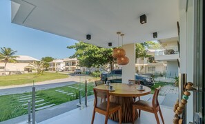 Ein Balkon mit einem runden Holztisch, Korbstühlen und einer hängenden Leuchte.