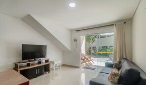 A modern living room with a flat-screen TV, a sofa, and a dining area. - Beautiful Apartment 130m From the Beach Mut0054 (Porto Seguro)