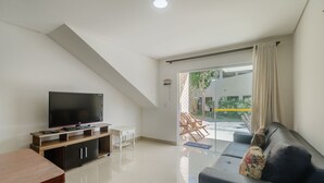 A modern living room with a flat-screen TV, a sofa, and a dining table. - Beautiful Apartment 130m From the Beach Mut0054 (Porto Seguro)