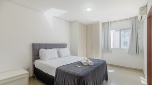 A neatly arranged bedroom with a bed, bedside tables, a wardrobe, and a window with curtains. - Beautiful Apartment 130m From the Beach Mut0054 (Porto Seguro)