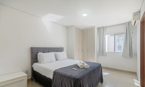A neatly arranged bedroom with a bed, bedside tables, a wardrobe, and a window with curtains. - Beautiful Apartment 130m From the Beach Mut0054 (Porto Seguro)