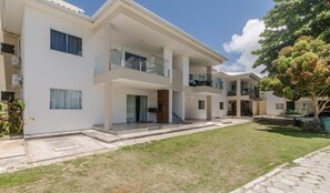 A modern multi-story residential building with a central courtyard, balconies, and a well-maintained lawn. - Beautiful apt Steps From Muta Beach Code Mut0047 (Porto Seguro)