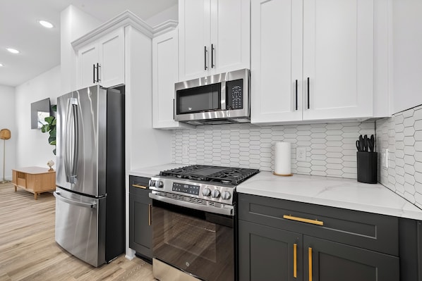 A modern kitchen with stainless steel appliances, a microwave, and a gas stove.