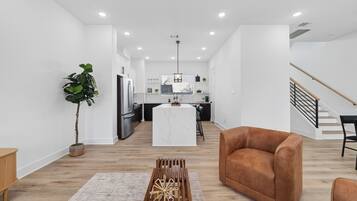 A modern living space with a kitchen, a dining area, and a staircase.