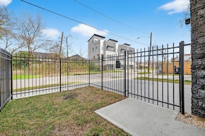 A gated residential area with a paved driveway leading to a modern two-story building.