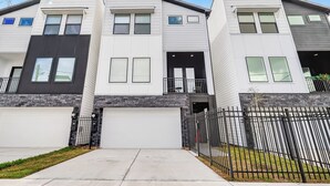Un immeuble résidentiel moderne à plusieurs étages, doté d’un garage, d’un balcon et d’une façade en pierre.