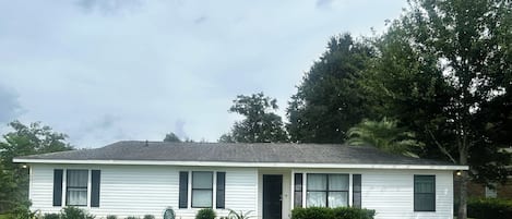 A single-story house with a front porch, a lawn, and a driveway.