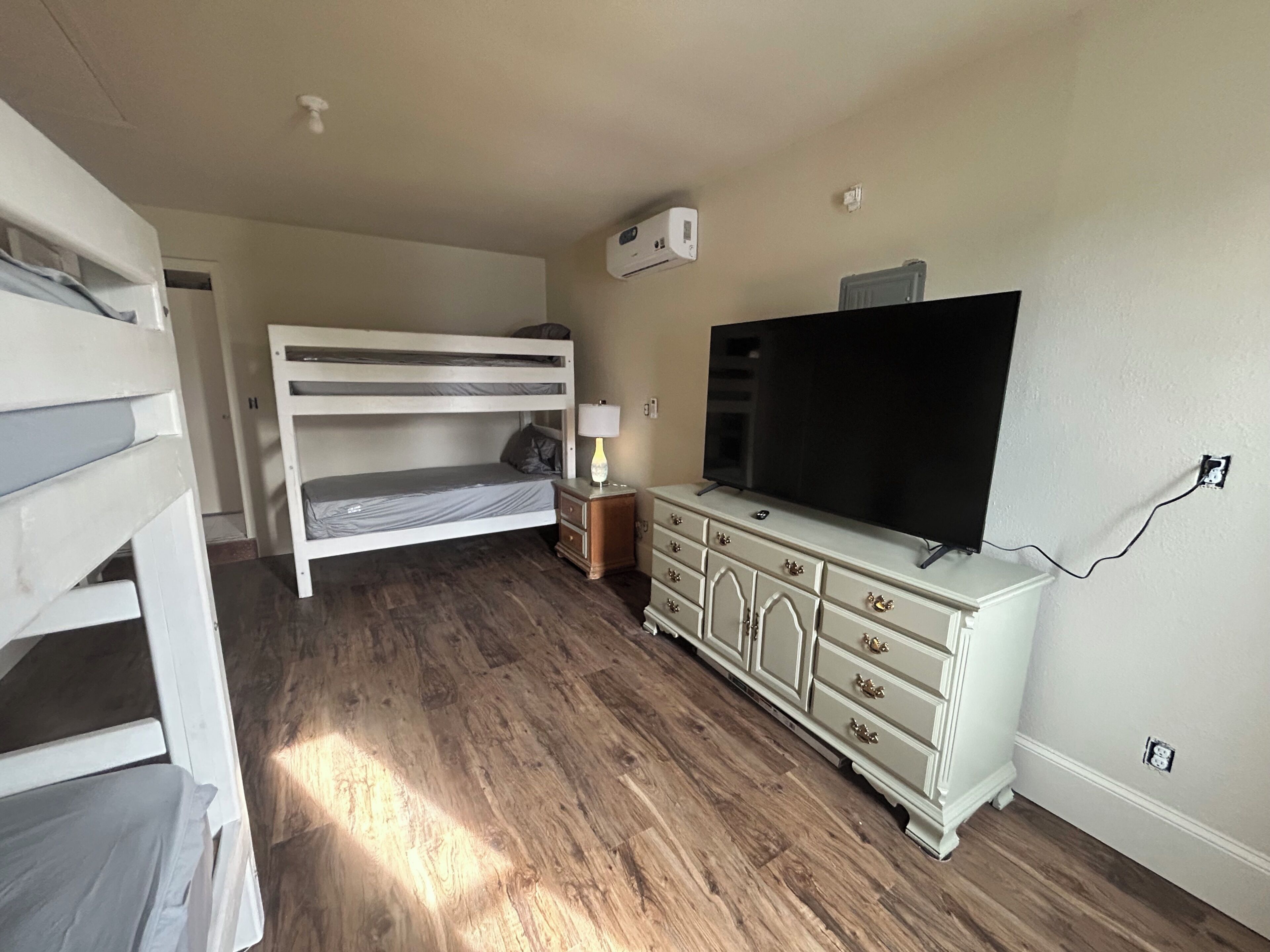 Een kamer met een stapelbed, een dressoir, een televisie en een luchtverkoeler aan de muur.