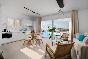 Eine moderne Wohnung mit Küche, Essbereich und einem Balkon mit Blick auf den Pool.