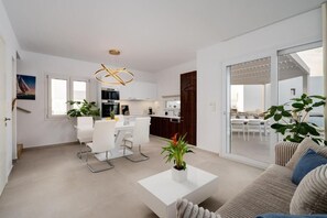 Een modern appartement met een eetgedeelte, keuken en woonkamer met een bank en salontafel.