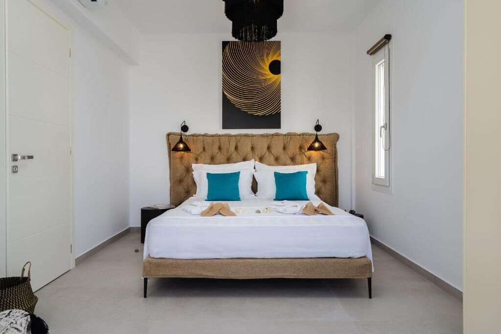 A bedroom with a large bed, two bedside lamps, a wall art piece, and a window.