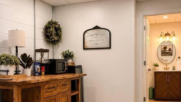 Een keuken met een houten kast, een magnetron en een klok aan de muur.