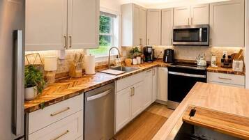 Una cocina moderna con armarios blancos, electrodomésticos de acero inoxidable y encimera de madera.