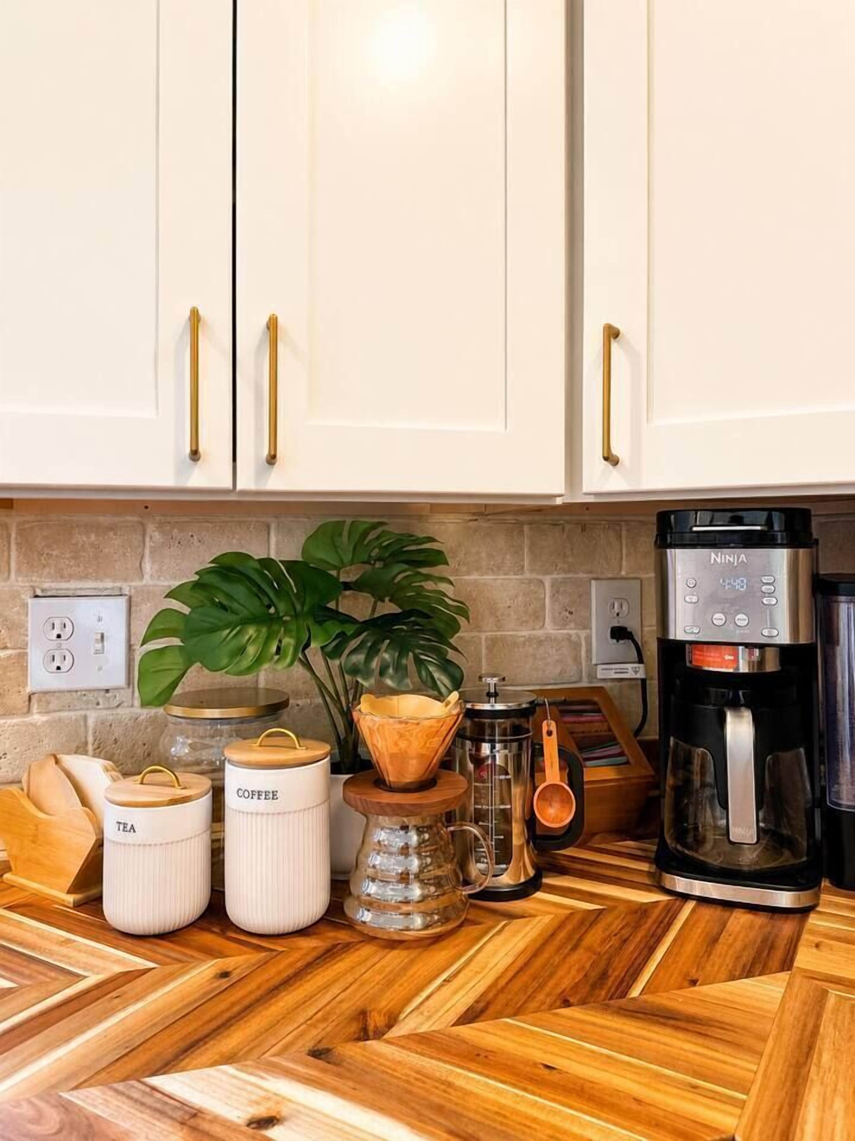 Una cocina con armarios blancos, una cafetera y varios recipientes.