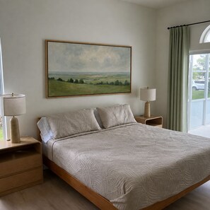 A bedroom with a large bed, two bedside tables with lamps, a painting on the wall, and a window with curtains. - Sand and Sage: 3BR, 2BH, Heated Pool, Fenced Yard (Spring Hill)