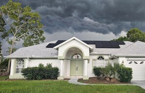 A single-story house with a front entrance, a garage, and a driveway. - Sand and Sage: 3BR, 2BH, Heated Pool, Fenced Yard (Spring Hill)