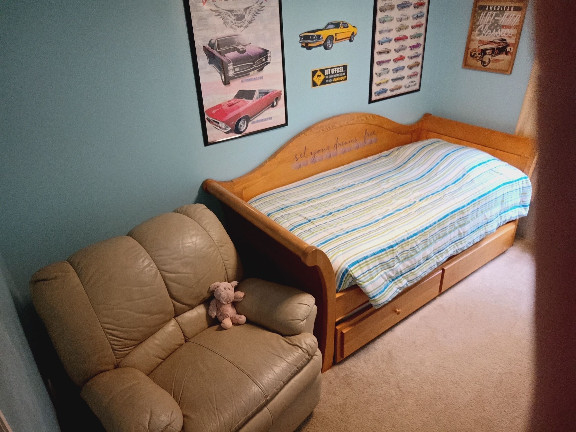 A bedroom with a bed, a chair, and wall decorations including car posters.