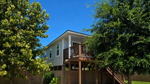 A two-story house with a deck, surrounded by a wooden fence and trees. - Pet Friendly, Short Drive to Beach, Nearby Stores! (Galveston)