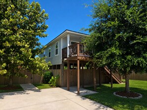 A two-story house with a deck, surrounded by a wooden fence and trees. - Pet Friendly, Short Drive to Beach, Nearby Stores! (Galveston)