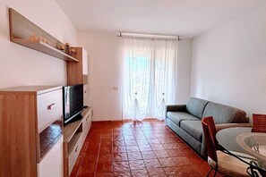 A living room with a television, sofa, and dining table. - Cozy vacation home 250 meters from the beach, with reserved parking and free Wi-Fi (Cannigione)